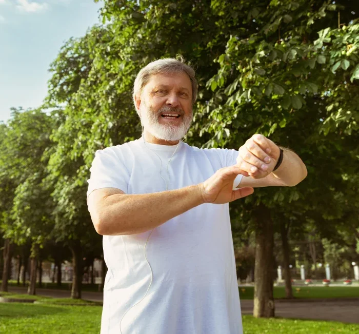 An older man outdoors glancing at his watch, suggesting a fixed daily habit